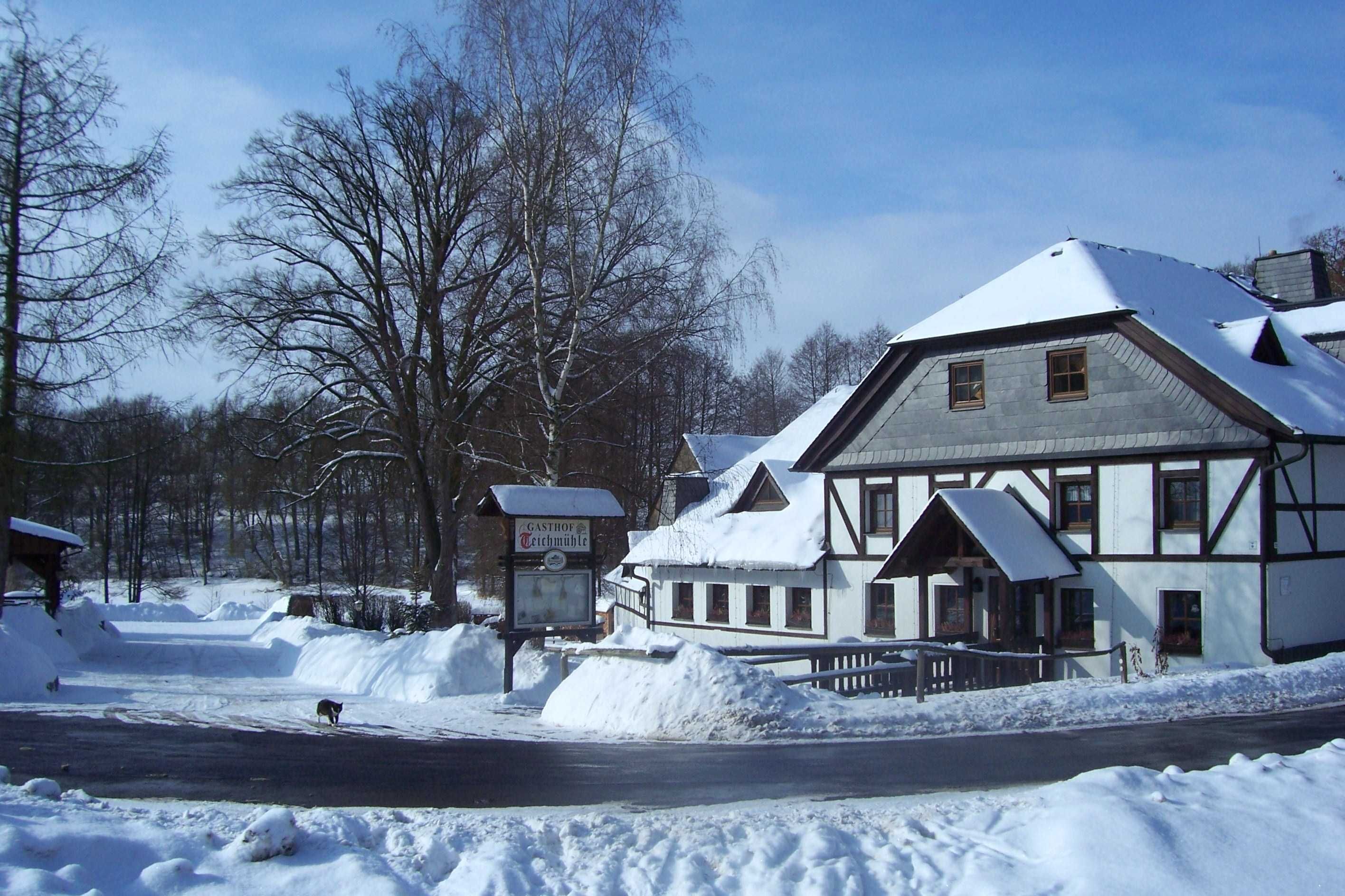 Ein schneebedecktes Gebäude mit einem Schild, auf dem 'Gastrop Teichmühle' steht.