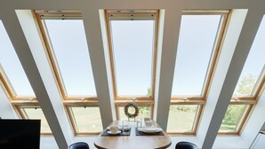 A dining area with a round table, two chairs, a television, and a view through large windows. - Der Besitz 6a (Stoltebuell)
