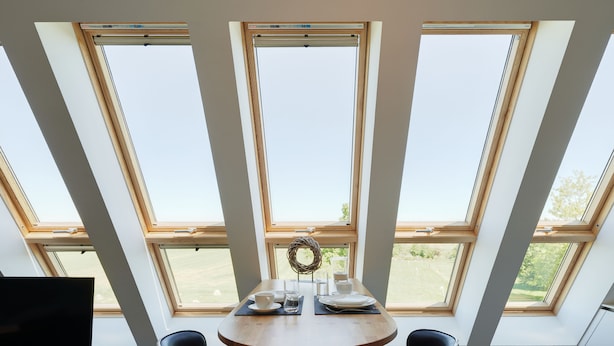 A dining area with a round table, two chairs, a television, and a view through large windows. - Der Besitz 6a (Stoltebuell)