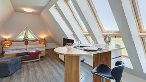 A modern loft bedroom with a skylight, a dining area with a round table, and a cozy seating area. - Der Besitz 6a (Stoltebuell)
