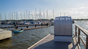 A marina with multiple boats docked, a wooden pier, and a covered seating area.