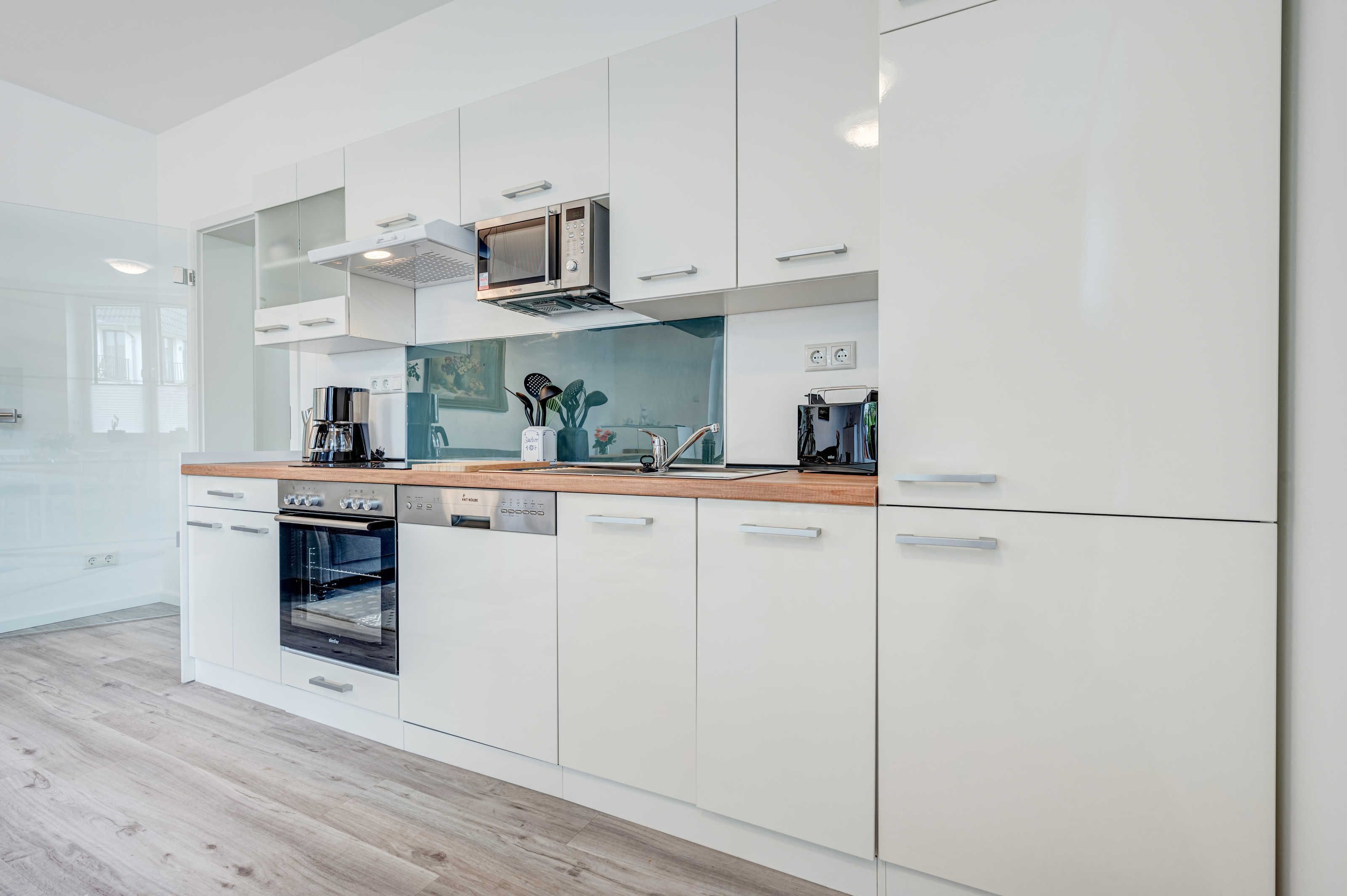 A modern kitchen with white cabinetry, a built-in oven, and a microwave.