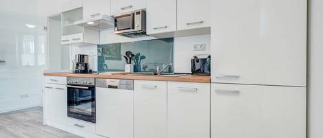 A modern kitchen with white cabinetry, a built-in oven, and a microwave.