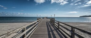 A wooden pier extending into calm waters with a clear sky.