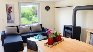 A modern living room with a sofa, a coffee table, a fireplace, and a view of the outdoors. - Ferienhaus Vietgest, Deutschland (Lalendorf)