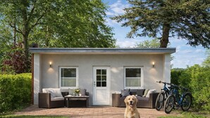 A small house with a porch, two windows, a door, a table with a dog, and bicycles. - Ferienhaus Vietgest, Deutschland (Lalendorf)