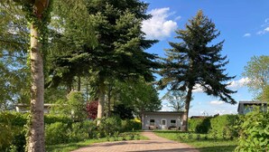 A paved pathway leading to a building surrounded by lush greenery and trees. - Ferienhaus Vietgest, Deutschland (Lalendorf)
