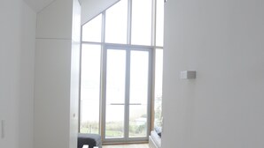 A modern interior with a staircase leading to a large glass door, white walls, and wooden flooring. - Seglerwohnung 8 (Kappeln)