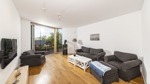 A modern living room with a wooden floor, grey sofas, a white coffee table, and a fireplace. - Seglerwohnung 8 (Kappeln)