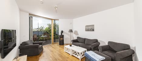 Una sala de estar moderna con piso de madera, sofás grises, una mesa de centro blanca y una chimenea.