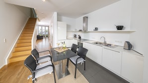 A modern kitchen with white cabinets, a black countertop, and a dining area with wicker chairs. - Seglerwohnung 8 (Kappeln)