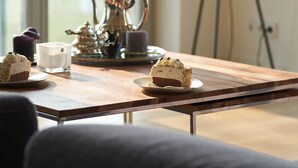 Una mesa de madera con un hervidor, tazas y un pastel.