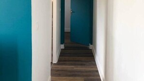 Un couloir étroit avec un plancher en bois et des murs de couleur turquoise.