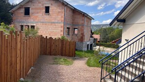 Un immeuble résidentiel à la façade en briques, doté d’une clôture en bois et d’un chemin de gravier menant à un escalier.