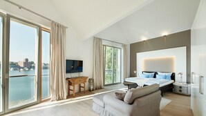 A modern bedroom with a large bed, a sofa, a desk, and a TV. - Kapitänsbrücke - Penthouse (Kappeln)