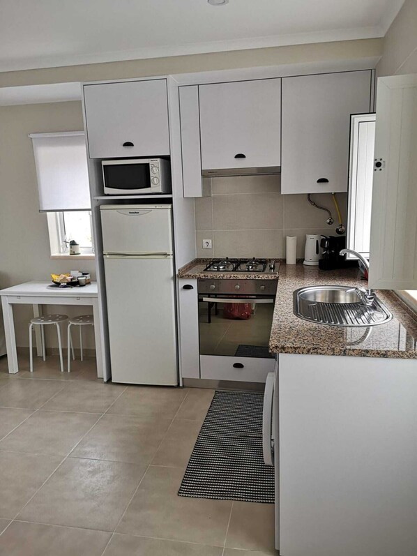 A compact kitchen with a built-in microwave, a gas stove, and a sink.
