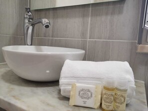 Un baño con un lavabo blanco, una toalla y dos botellas de jabón.