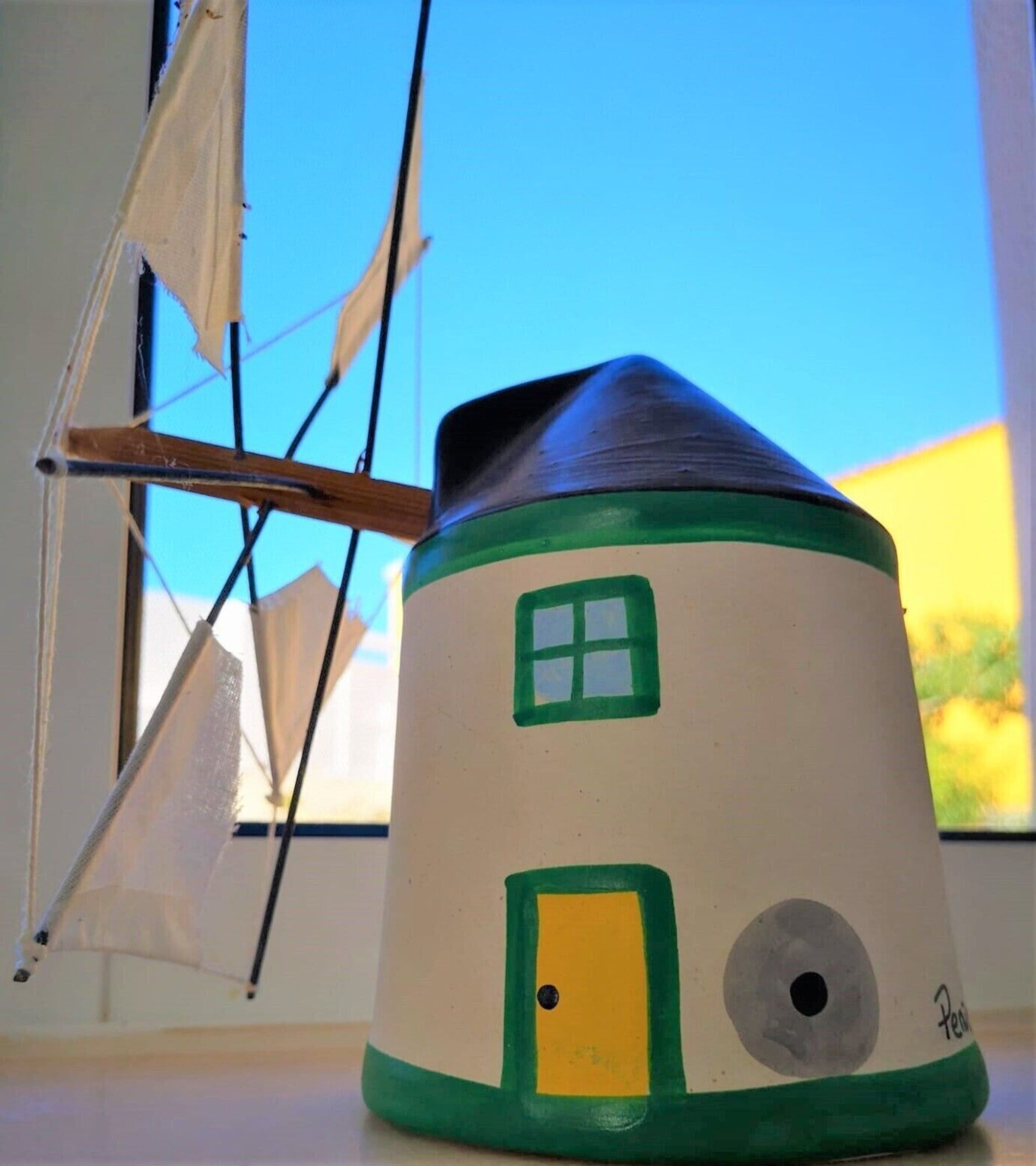 A model house with a conical roof, a window, and a door.
