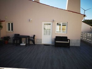 A patio with a table and chairs, a bench, a door, and windows. - Feather House FH Lace (São Bartolomeu de Galegos)