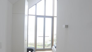 A modern interior with a staircase leading to a balcony, large windows, and a minimalist design. - Seglerwohnung 9 (Kappeln)