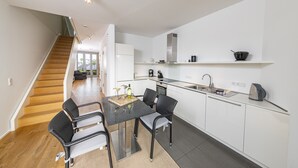 A modern kitchen with white cabinets, a black countertop, and a dining area with wicker chairs. - Seglerwohnung 9 (Kappeln)