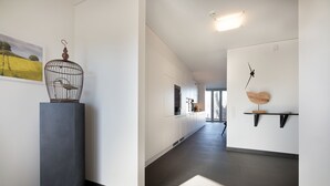 Un couloir moderne agrémenté d’une sculpture en forme de cage à oiseaux, d’une horloge et d’une feuille décorative sur le mur.