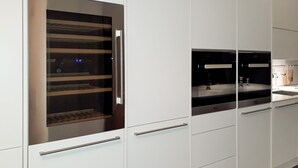 Une cuisine moderne avec des meubles blancs, un four encastré et une hotte de cuisinière en acier inoxydable.