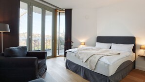 Une chambre moderne avec un grand lit, un canapé et une vue à travers une porte vitrée.