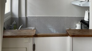 A kitchen with white cabinets, a patterned backsplash, and wooden countertops.