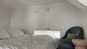 A bedroom with a bed, a chair, and a window.