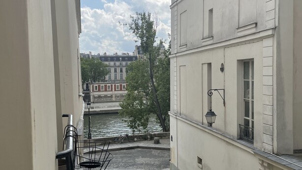 A narrow street with a river, buildings on both sides, and a clear sky.