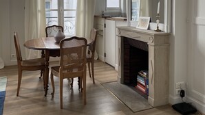 A dining area with a round table and four chairs, a fireplace with a mantel, and a large mirror above it.
