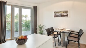 A dining area with a table set for four, a fruit bowl, and a potted plant. - Steuermann (Kappeln)