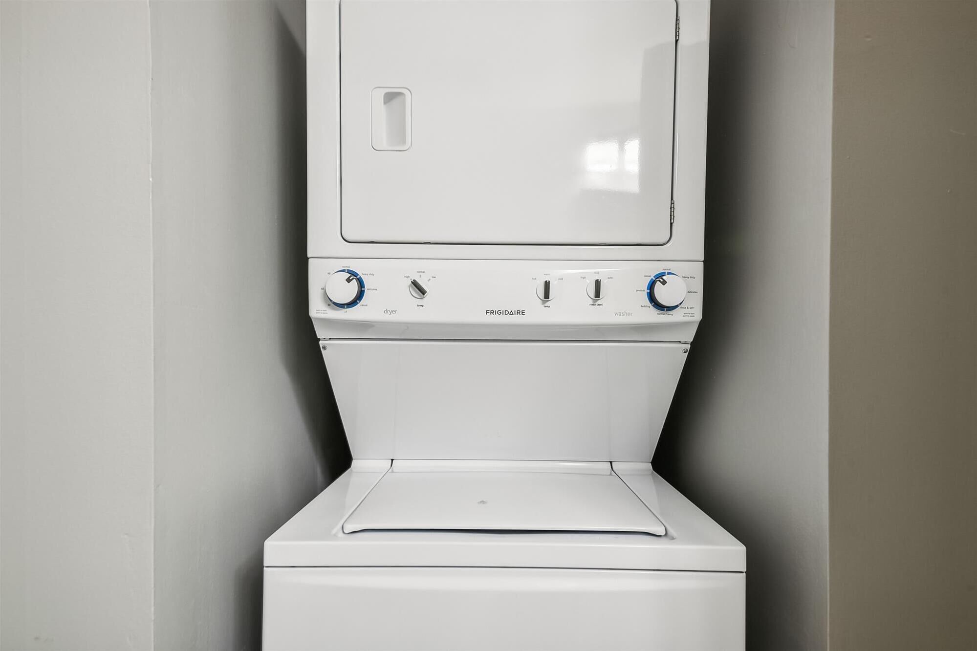 A white, wall-mounted washer and dryer unit with control knobs and a door.