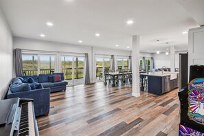 Un vaste espace de vie comprenant un grand canapé, une table à manger et un coin cuisine avec un évier et un îlot central.