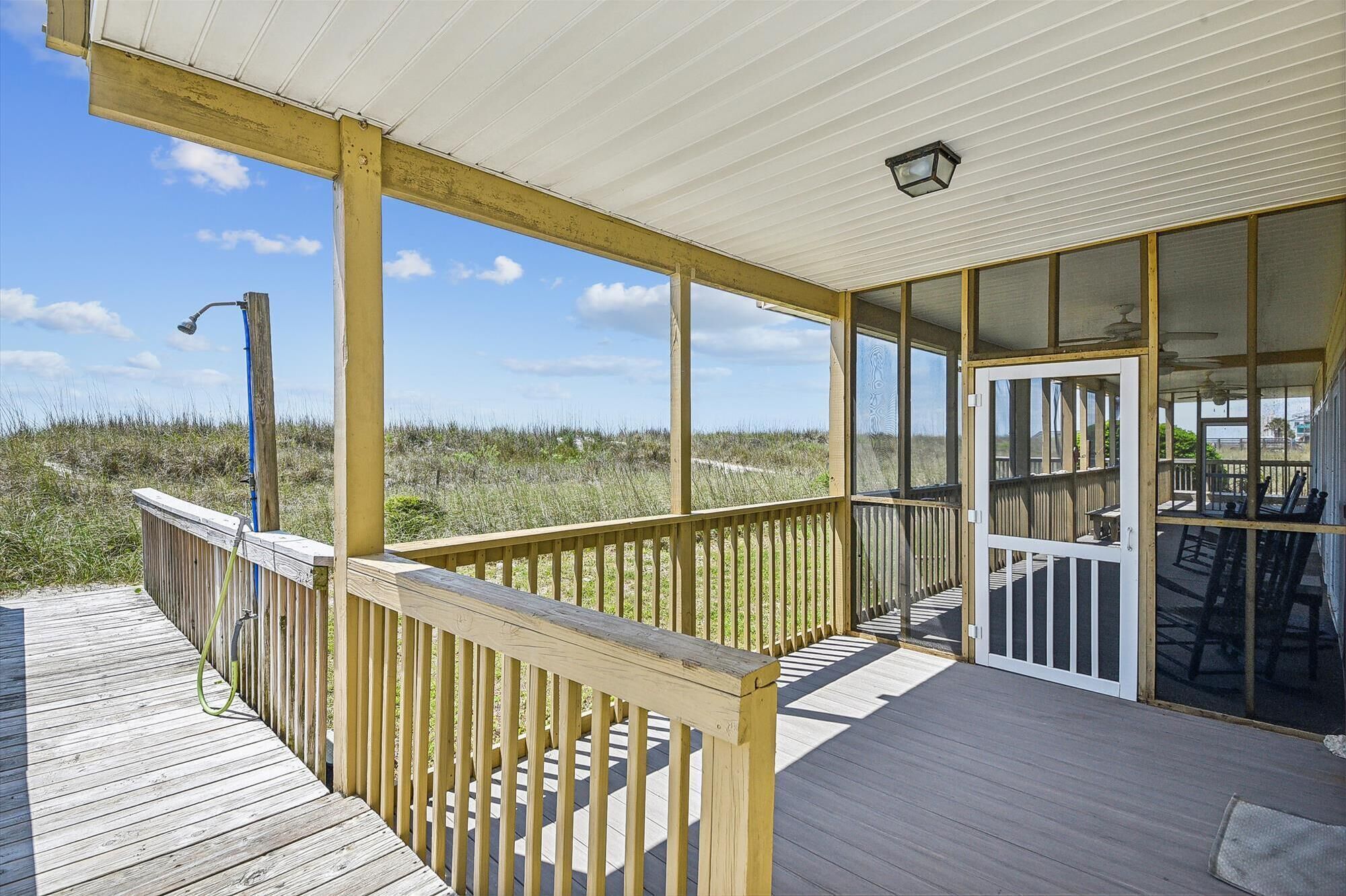 A wooden deck with a glass door leading to an outdoor seating area.