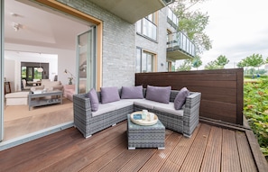 A modern outdoor living area with a sectional sofa, a small table, and a wooden deck. - Lotsenhaus 11 (Kappeln)