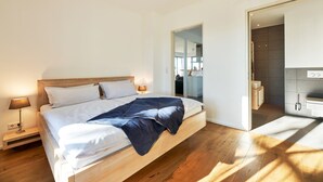 Un dormitorio moderno con una cama de madera, ropa de cama blanca y un plaid oscuro.