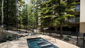 A swimming pool with steps, surrounded by a fence, and trees. - Ski OR Walk to Lifts, Village and Hot Tub! Luxurious & Clean Beaver Creek Condo (Beaver Creek)