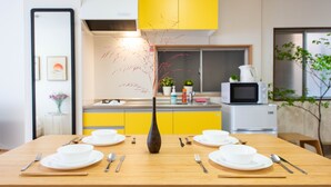 A dining table set with white plates, silverware, and a vase with red branches. - TORA HOTEL Taito D (Tokyo)
