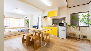 A modern kitchen with a dining area, wooden flooring, and a view of the living room. - TORA HOTEL Taito D (Tokyo)