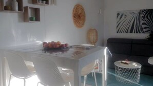 A modern dining area with a white table, white chairs, a zebra print wall art, and a round woven side table.
