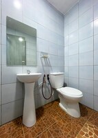Un baño con azulejos blancos, un lavamanos pedestal, un inodoro y un espejo.