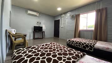 A hotel room with two beds, a television, an air conditioning unit, and a window with curtains.