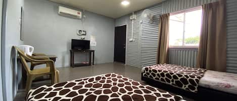 A hotel room with two beds, a television, an air conditioning unit, and a window with curtains.