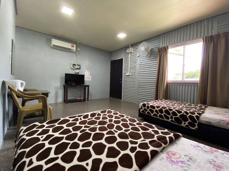 A hotel room with two beds, a television, an air conditioning unit, and a window with curtains.
