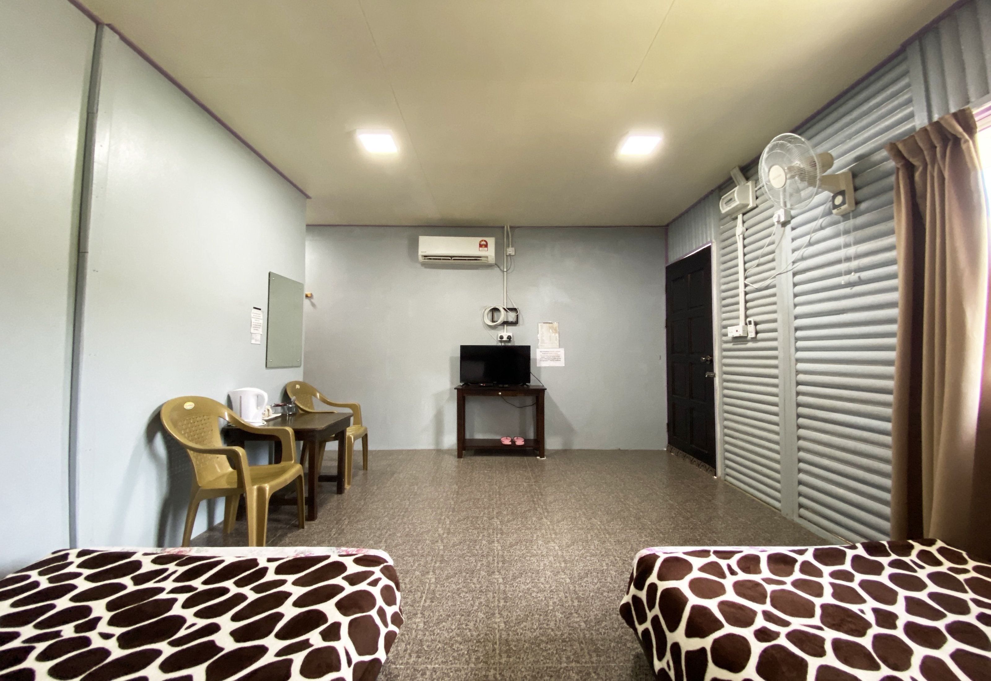 A room with two beds, a television, a small table, and a window with curtains.
