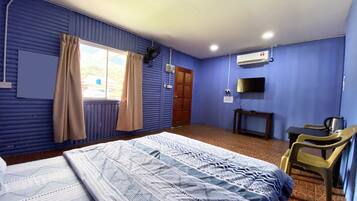 Una habitación con cama, escritorio, silla, televisor y aire acondicionado.