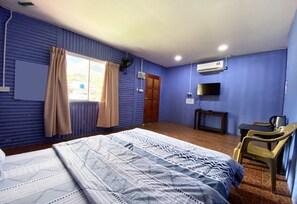 Una habitación con cama, escritorio, silla, televisor y aire acondicionado.