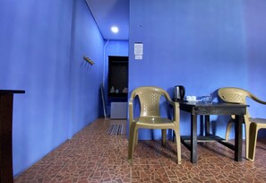 Una habitación con paredes azules, piso de baldosas, una mesa con sillas, un refrigerador y un letrero en la pared.